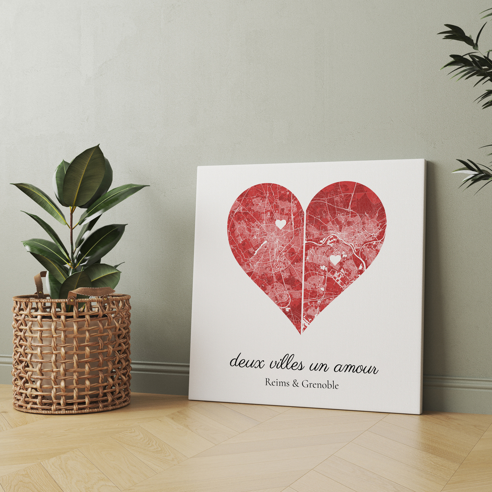 Toile de deux villes en cœur rouge, posée au sol près d'une plante, une idée cadeau pour un couple à distance